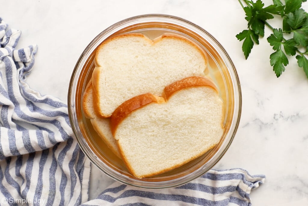 overhead of bread soaking in a bowl of water