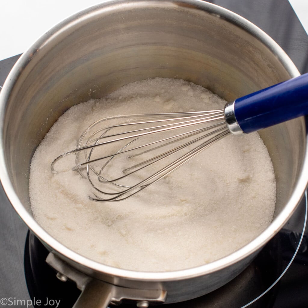 Overhead view of a pot with sugar and a whisk for caramel sauce recipe - 7