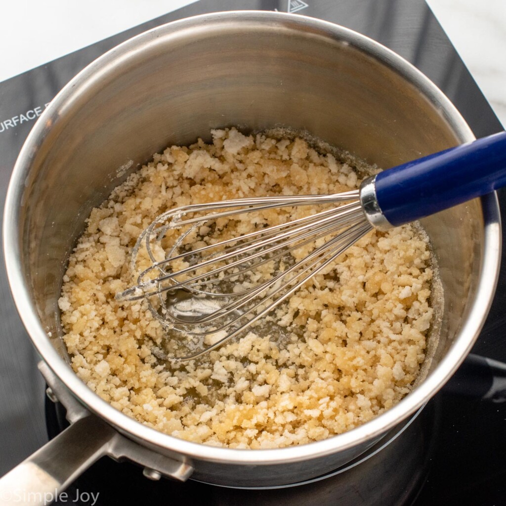 Photo of a pot with sugar that is cooking for caramel sauce recipe with a whisk