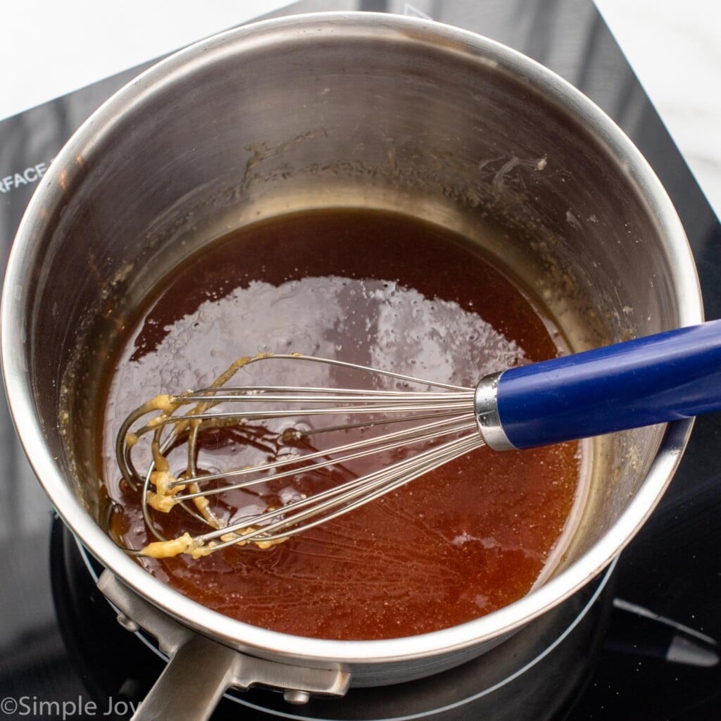 Overhead view of a pot with melted sugar for caramel sauce recipe and a whisk