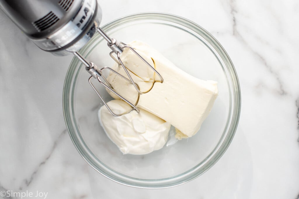 Overhead view of a mixing bowl with ingredients for Clam Dip recipe with beaters in it. - 4