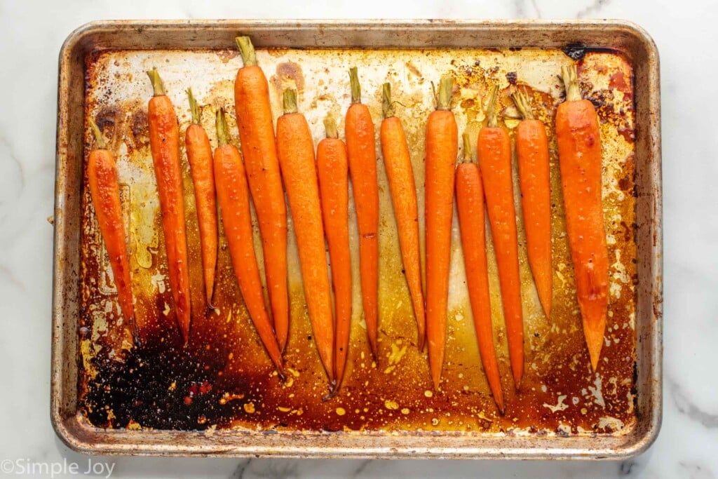 Overhead view of a baking sheet with seasoned carrots for Honey Roasted Carrots recipe