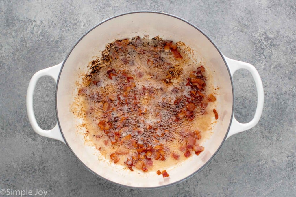 Overhead view of a pot of bacon pieces cooking for Manhattan Clam Chowder recipe. - 6