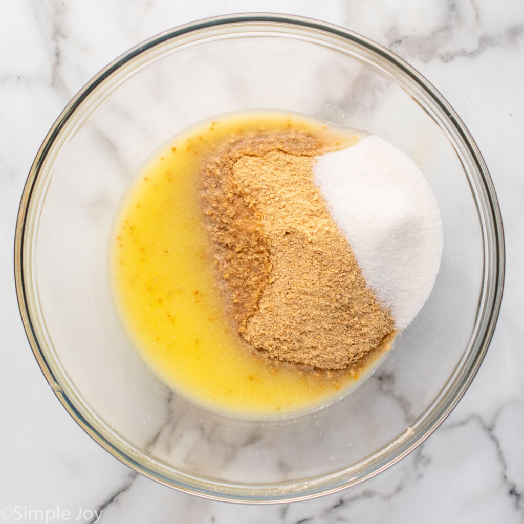 Overhead view of a mixing bowl of ingredients for crust of No Bake Cheesecake recipe. - 7