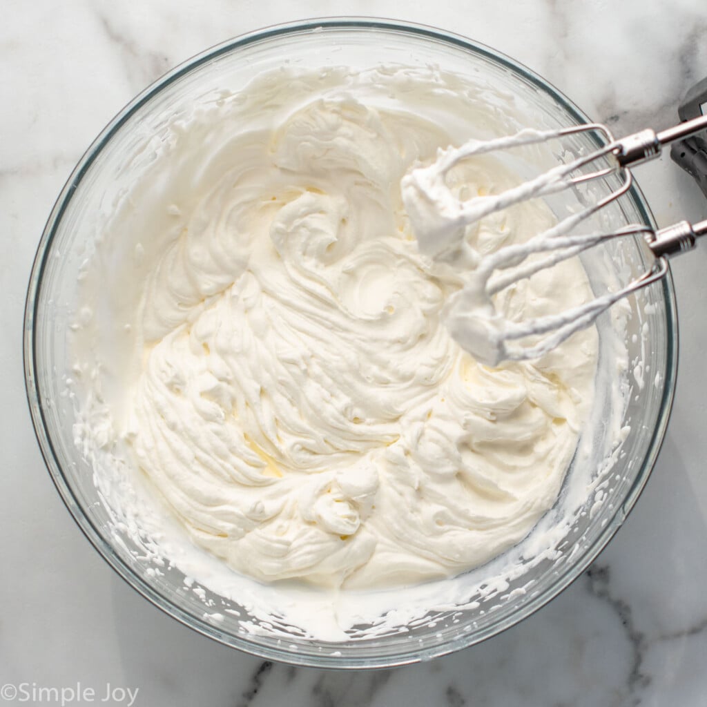 Overhead view of a mixing bowl of whipped filling with beaters for No Bake Cheesecake recipe. - 10