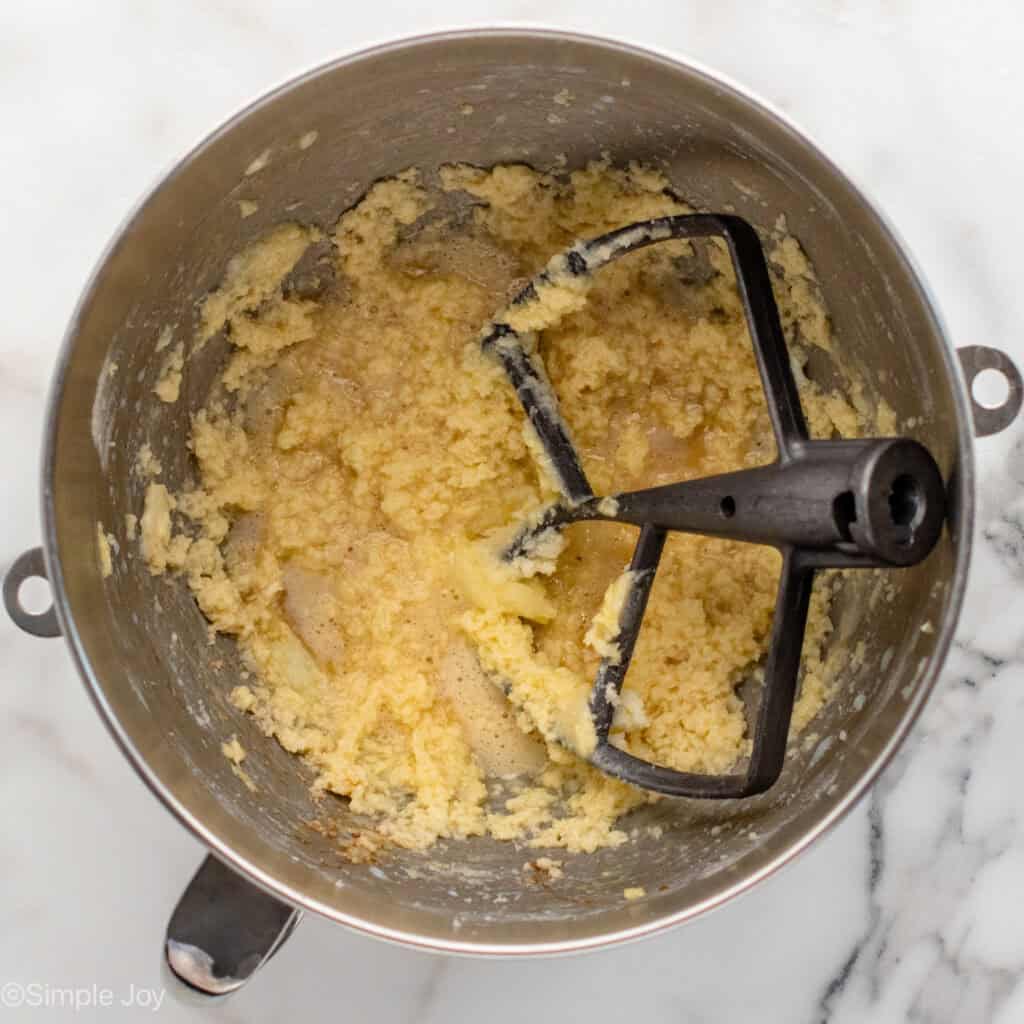 overhead of milk added to creamed butter and sugar in a mixing bowl
