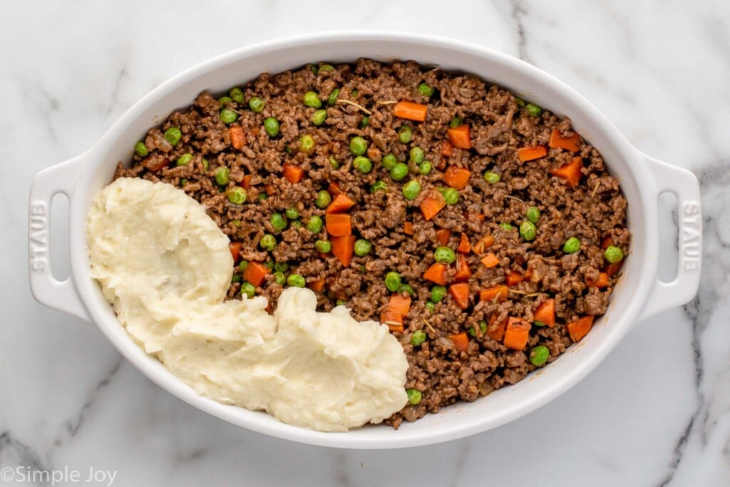 Overhead view of a baking dish of Shepherd's Pie recipe with some scoops of mashed potatoes on top. - 10