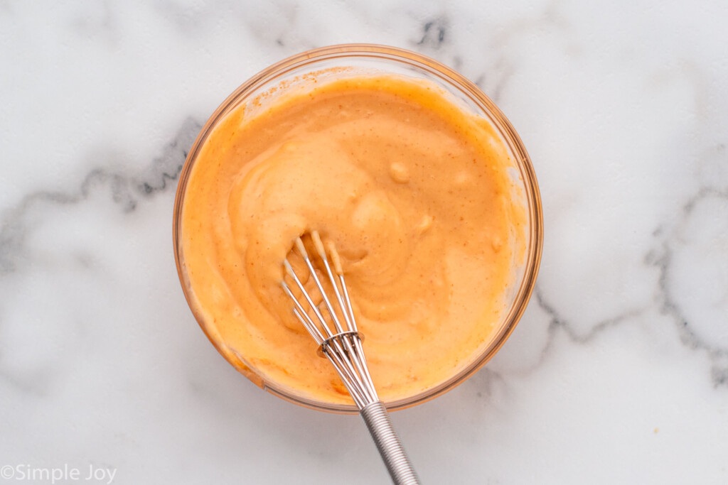 Overhead view of mixing bowl of sriracha mayo with whisk for Sushi Bowl recipe.