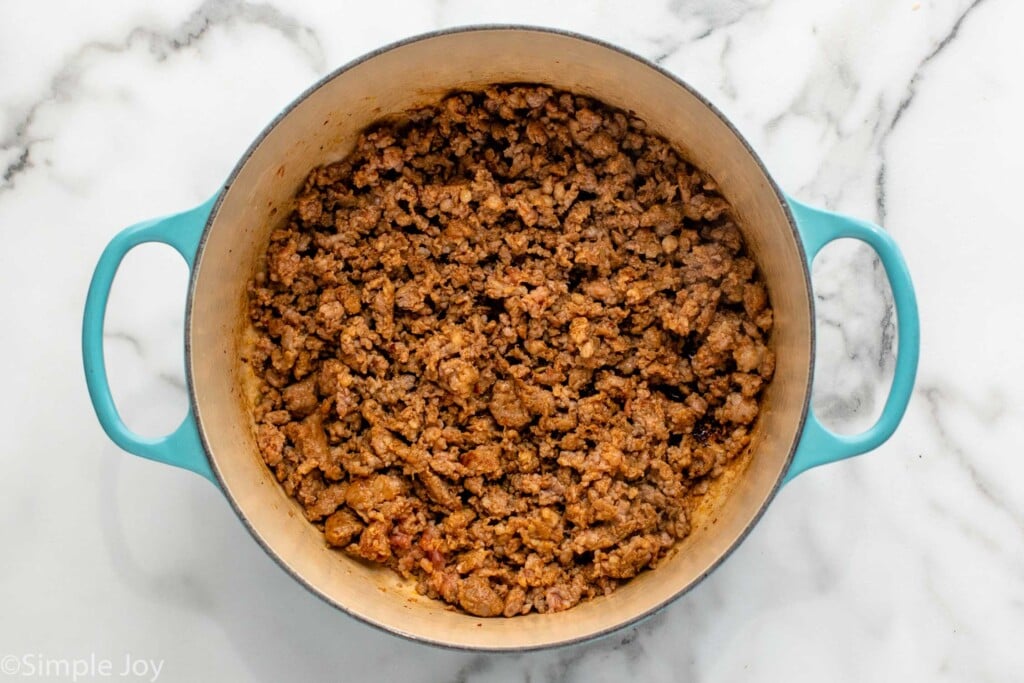 Overhead view of a pot of meat cooked for Zuppa Toscana recipe. - 6