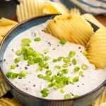 Bowl of Clam Dip garnished with chopped green onions with potato chips - 8