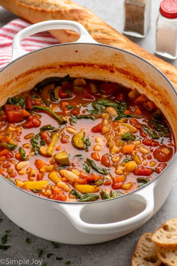 Pot of minestrone soup with bread beside. - 5