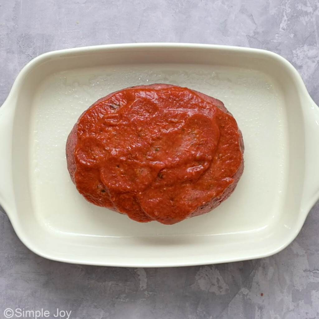 italian meatloaf in a pan topped with sauce before baking - 6