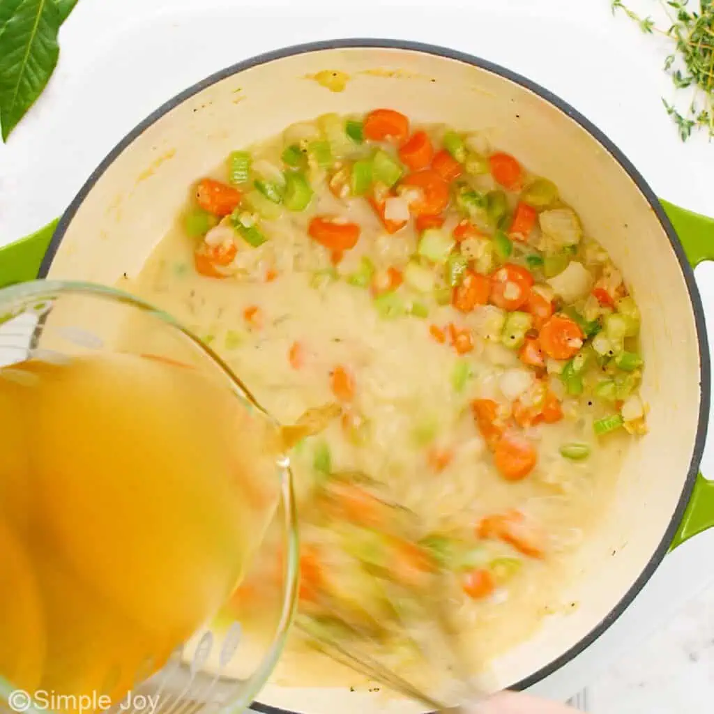 adding chicken stock to a pot of veggies