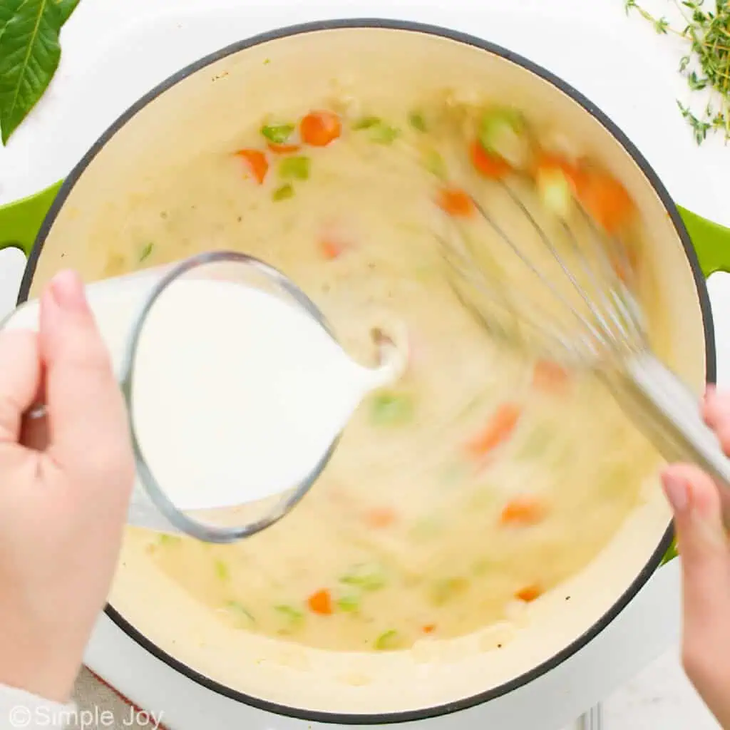 adding cream to a broth with vegetables