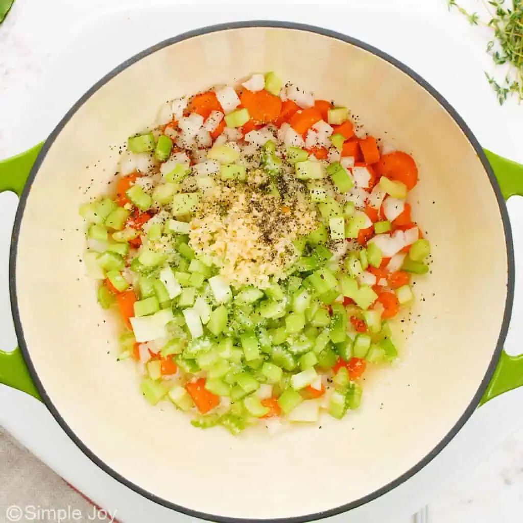carrots, celery, onion, and garlic being sautéed in a soup pot