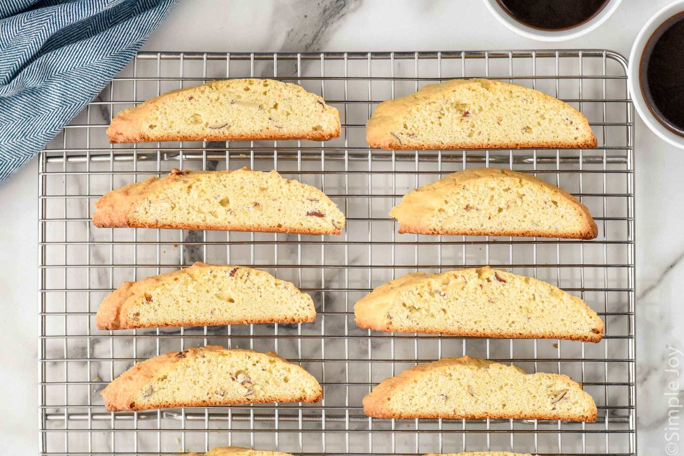 Overhead photo of Biscotti on cooling rack with cups of coffee beside