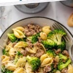 Pinterest graphic for Sausage Broccoli Pasta recipe. Text says, "the best Sausage Broccoli Pasta simplejoy.com." Image is overhead view of a bowl of Sausage Broccoli Pasta garnished with shredded parmesan cheese, with fork.