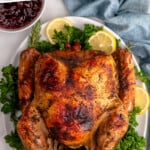 Pinterest graphic for turkey brine recipe. Text says, "the very best turkey recipe simplejoy.com." Image shows overhead view of cooked turkey made with turkey brine recipe on a platter with lemons and greens as garnish.