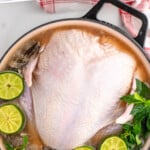 Pinterest graphic for turkey brine recipe recipe. Text says, "how to: brine a turkey simplejoy.com." Image is overhead view of a large pot with a raw turkey and turkey brine recipe.