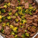 Overhead view of a skillet of easy Beef and Broccoli with sesame seeds and chopped green onions - 25
