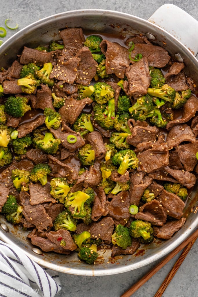 Overhead view of a skillet of easy Beef and Broccoli with sesame seeds and chopped green onions