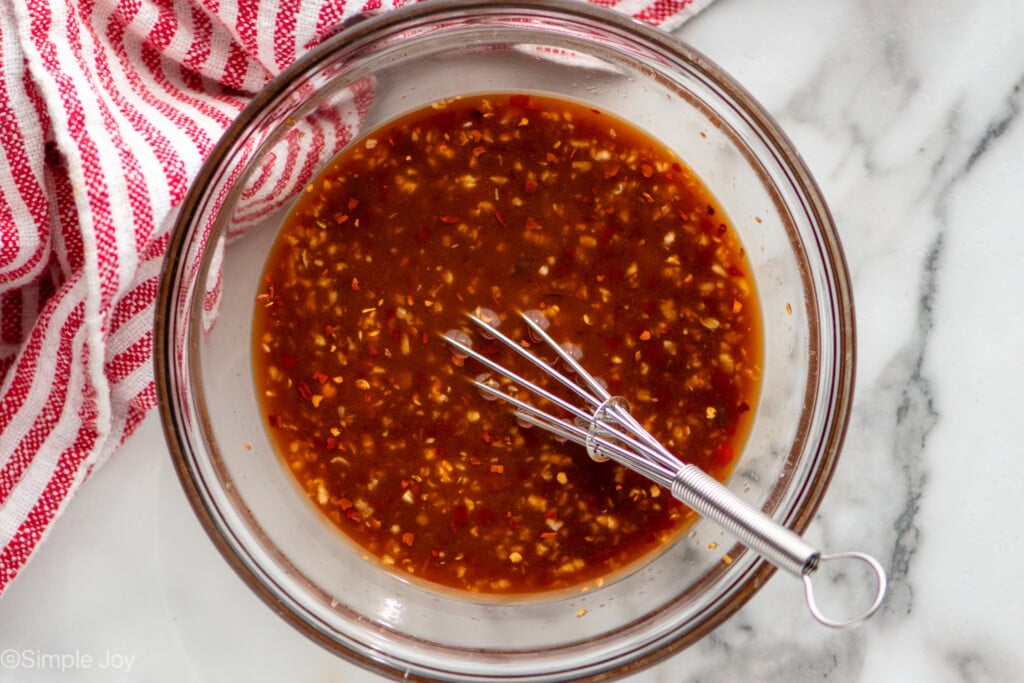 Overhead view of a glass mixing bowl of easy Beef and Broccoli sauce with a whisk