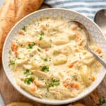 Bowl of chicken gnocchi soup with spoon. Bread beside. - 15