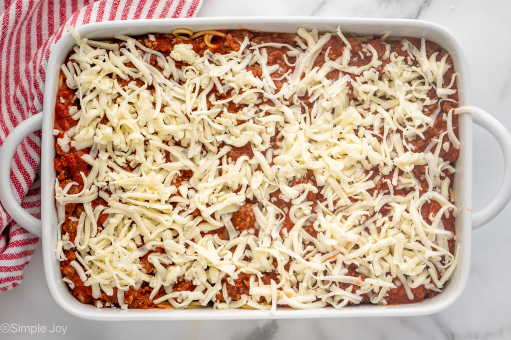 Overhead view of a baking dish of Baked Spaghetti recipe with shredded cheese on top before baking.