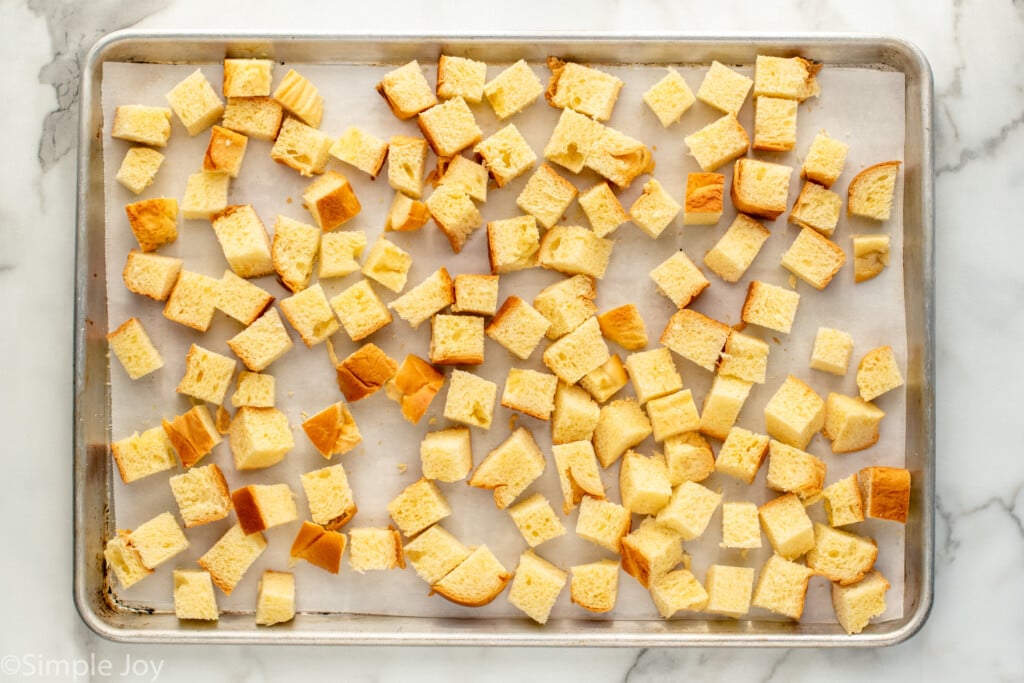 Overhead view of cubes of bread on baking sheet for Bread Pudding recipe. - 6