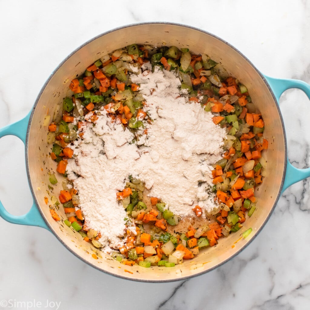 Overhead view of a pot of chopped vegetables and seasonings with flour for chicken gnocchi soup recipe.