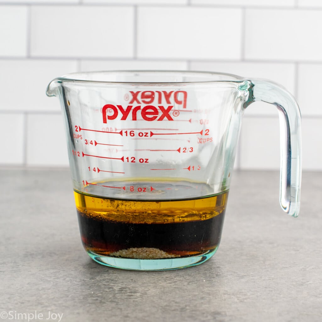 Side view of a glass measuring cup of Winter Salad dressing incredients. - 5