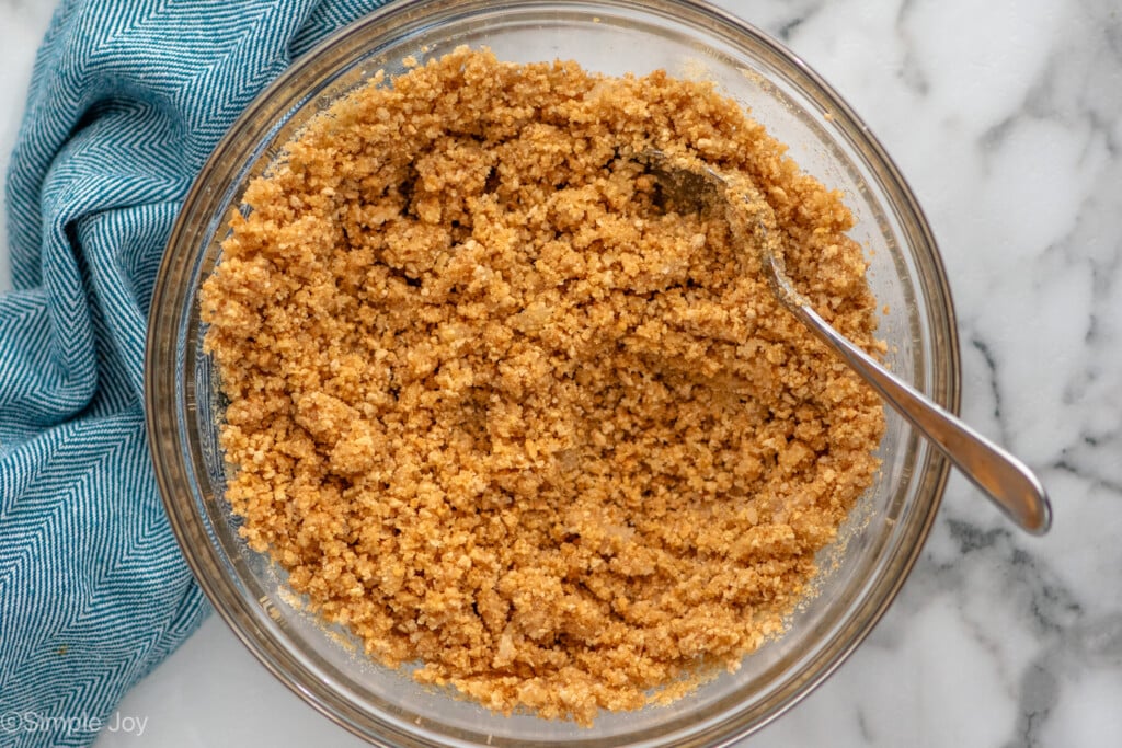 Overhead view of a mixing bowl of graham cracker crust recipe with a spoon
