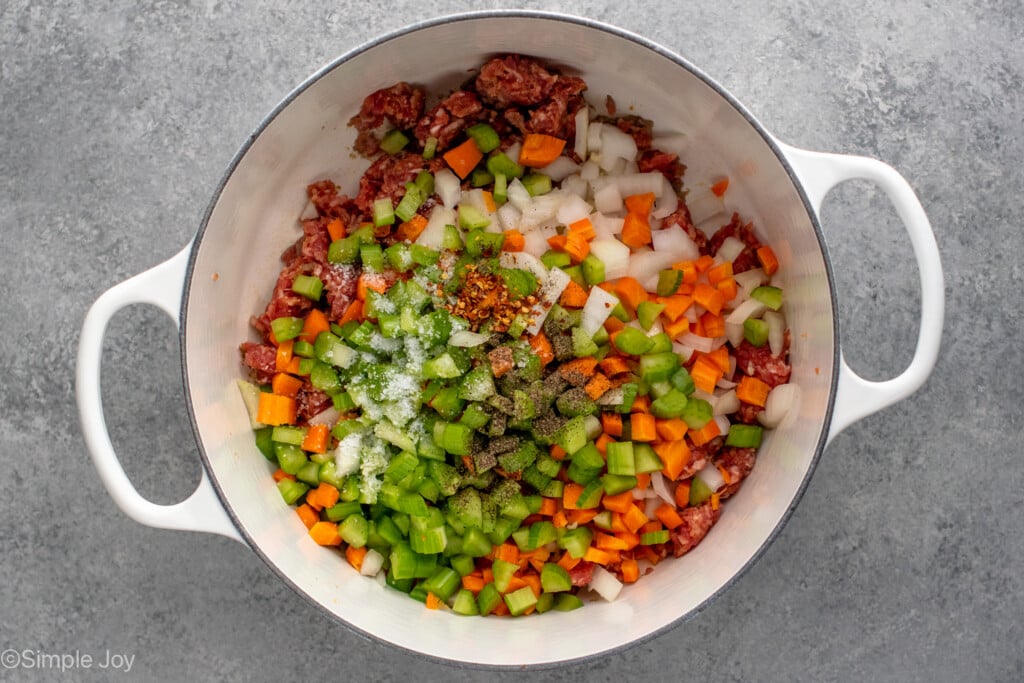 Overhead view of a pot of ingredients for Lasagna Soup recipe with chopped vegetables, seasonings, and ground beef.