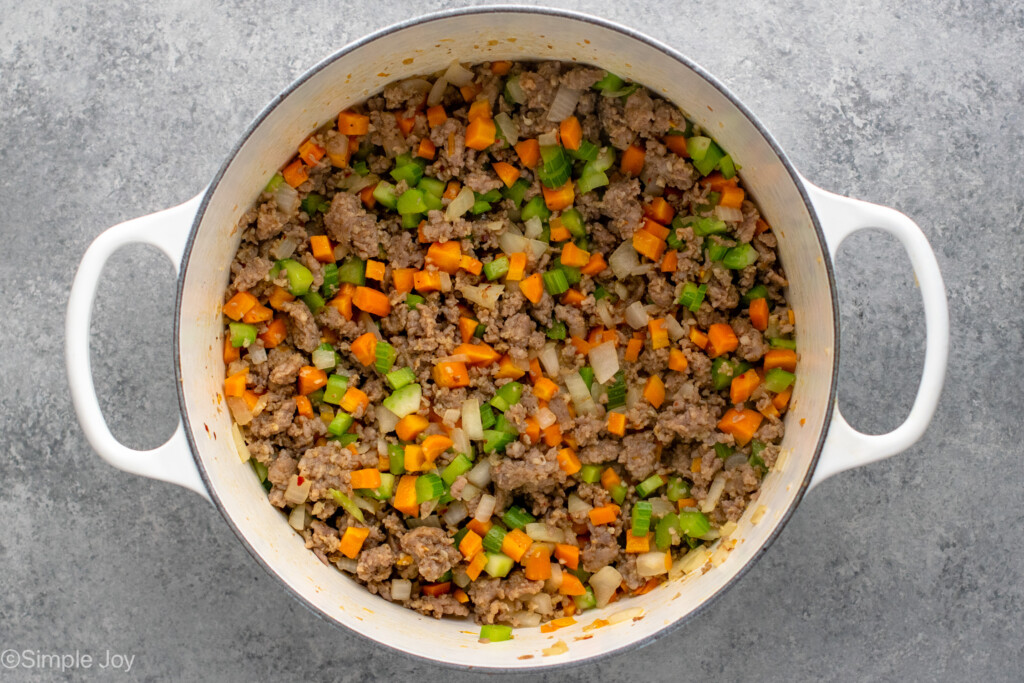 Overhead view of a pot of ingredients for Lasagna Soup recipe including cooked ground beef, chopped vegetables, and seasonings.