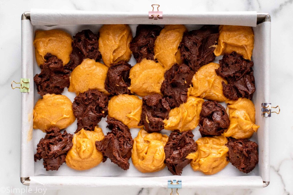 Overhead view of batter dropped into baking dish for Pumpkin brownies recipe. - 11