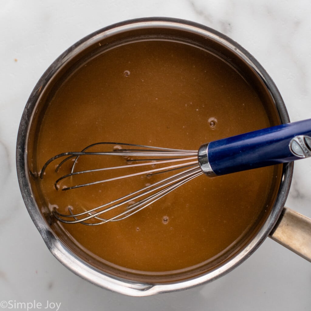 Overhead view of a saucepan of ingredients and whisk for Bread Pudding recipe.