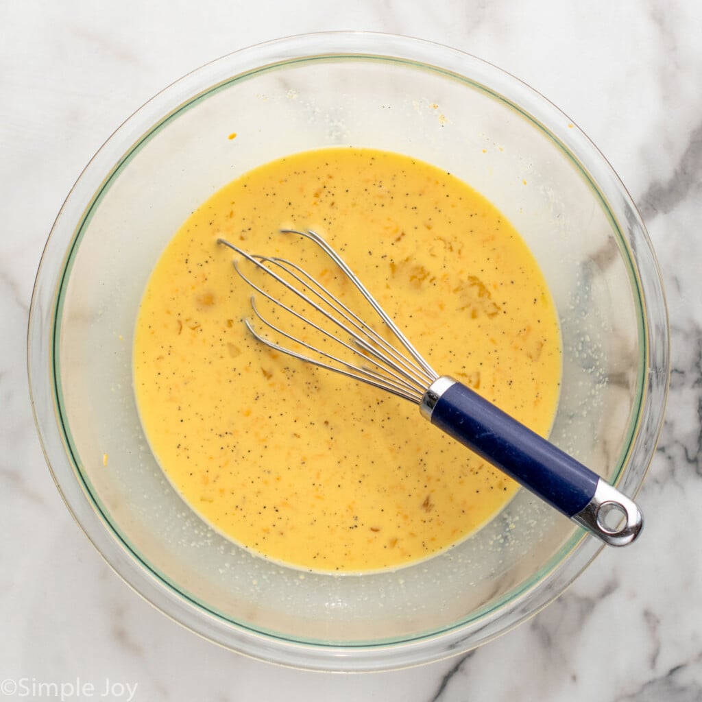 Overhead view of a mixing bowl and whisk with egg mixture for tater tot breakfast casserole recipe