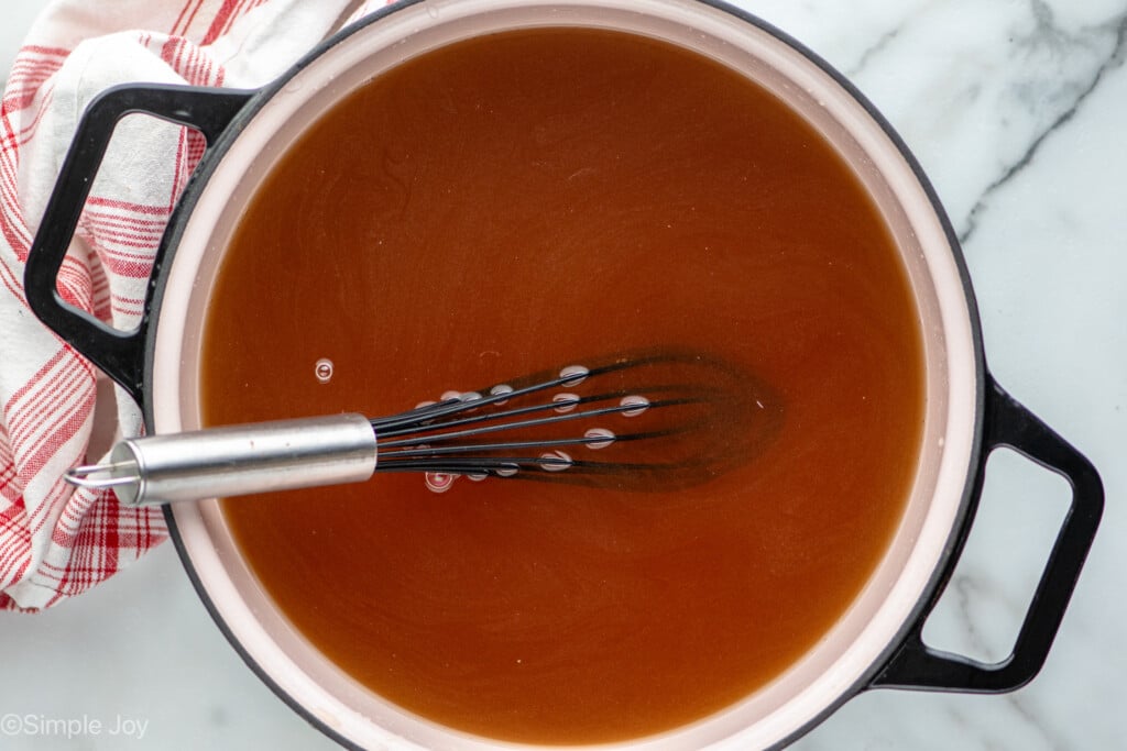 Overhead view of a large pot with liquid and a whisk for turkey brine recipe