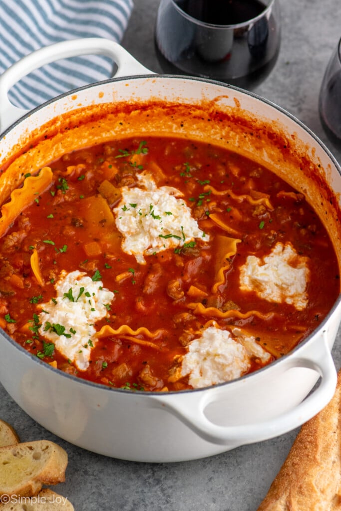 Pot of Lasagna Soup with bread and glasses of red wine beside.