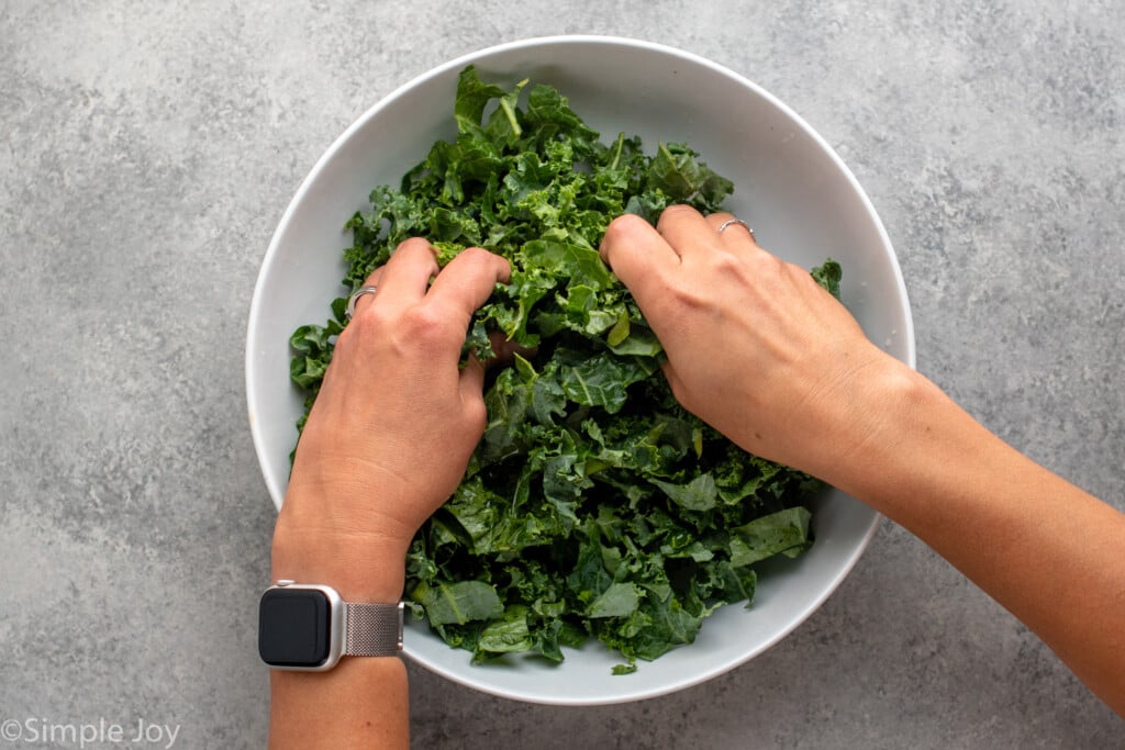 Overhead view of person's hands massaging bowl of kale for Winter Salad recipe. - 6