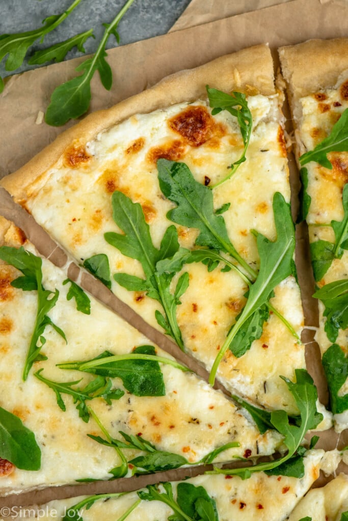 Close up view of slices of White Pizza garnished with arugula. - 9