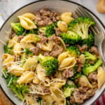 Overhead view of a bowl of Sausage Broccoli Pasta garnished with parmesan cheese with a fork. Glass of red wine beside. - 12