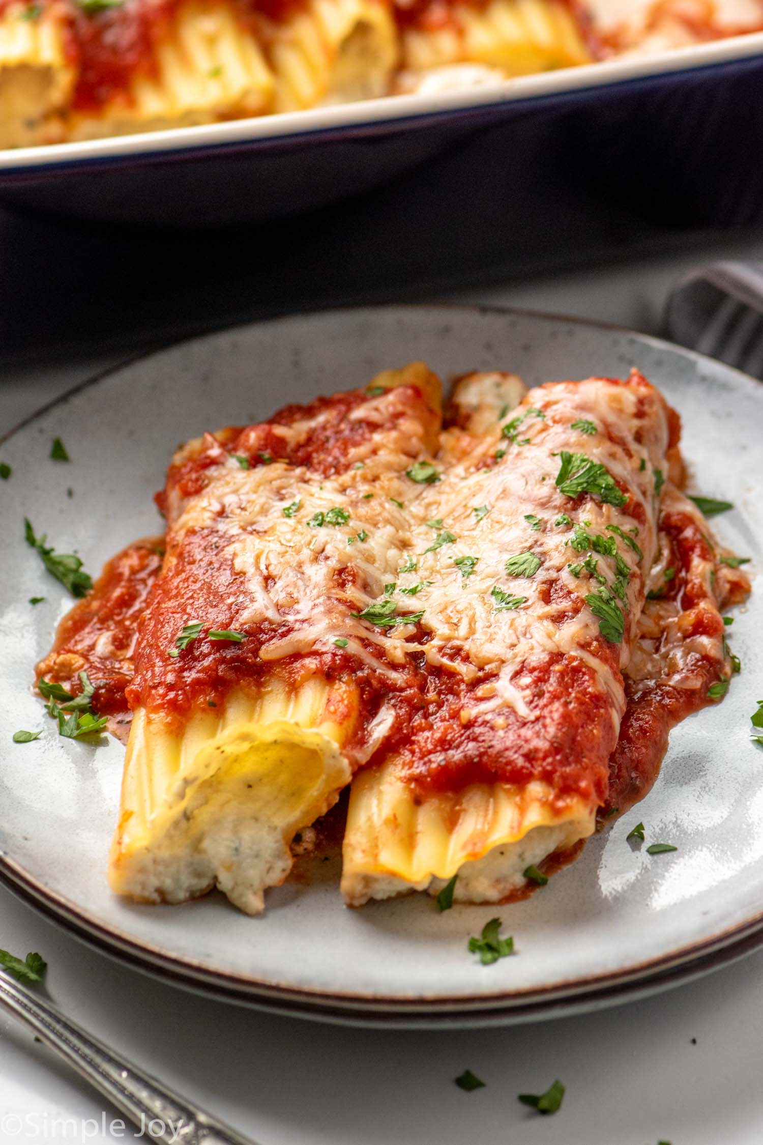 Cheese manicotti served on plate garnished with parsley flakes