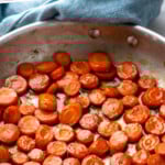 Pinterest graphic for candied carrots recipe. Text says, "the best candied carrots simplejoy.com." Image shows a skillet of candied carrots.