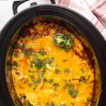 Pinterest graphic for Crockpot Chicken Enchilada Casserole recipe. Text says, "slow cooker enchilada casserole simplejoy.com." Image shows overhead view of slow cooker with Crockpot Chicken Enchilada Casserole recipe topped with cilantro and jalapenos.