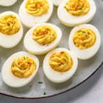 Pinterest graphic for Deviled Eggs recipe. Image shows platter of Deviled Eggs garnished with paprika and chopped chives. Text says, "the best Deviled Eggs simplejoy.com."