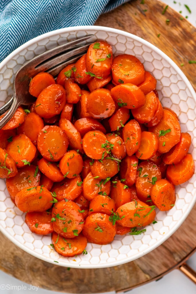 Overhead view of a skillet of candied carrots with forks - 4
