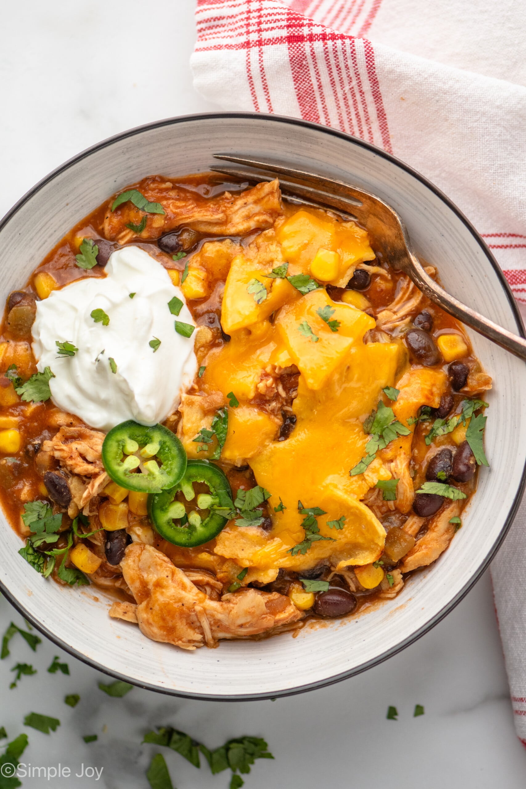 Overhead view of a bowl of Crockpot Chicken Enchilada Casserole topped with jalapenos and sour cream