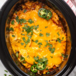 Overhead view of a crockpot of Crockpot Chicken Enchilada Casserole recipe, topped with cilantro and jalapenos - 10