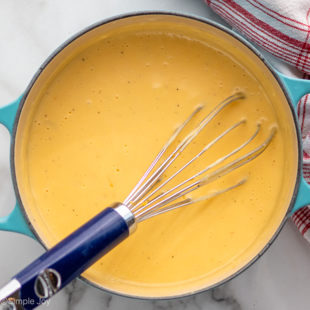 Overhead view of a pot of sauce for Potatoes Au Gratin recipe with a whisk